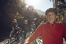 Ein Radfahrer im Vordergrund und weitere Radfahrer stehen dahinter 